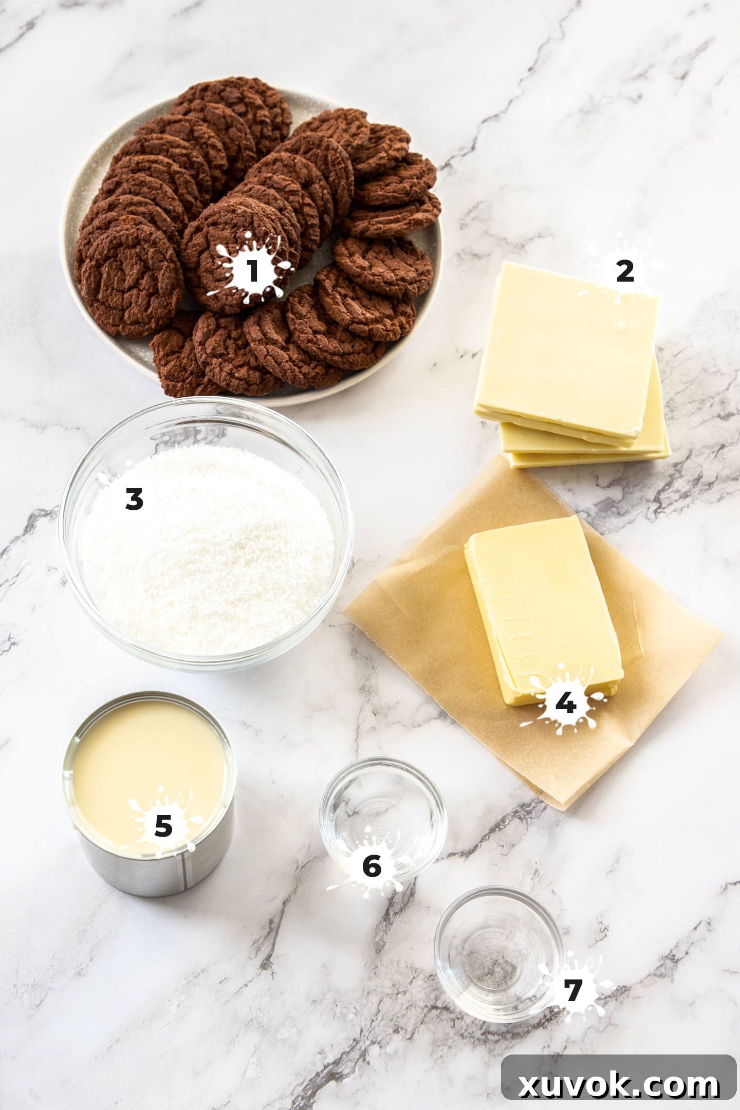 A flat lay of ingredients for peppermint coconut fudge, including condensed milk, chocolate, butter, and extracts, on a marble surface.