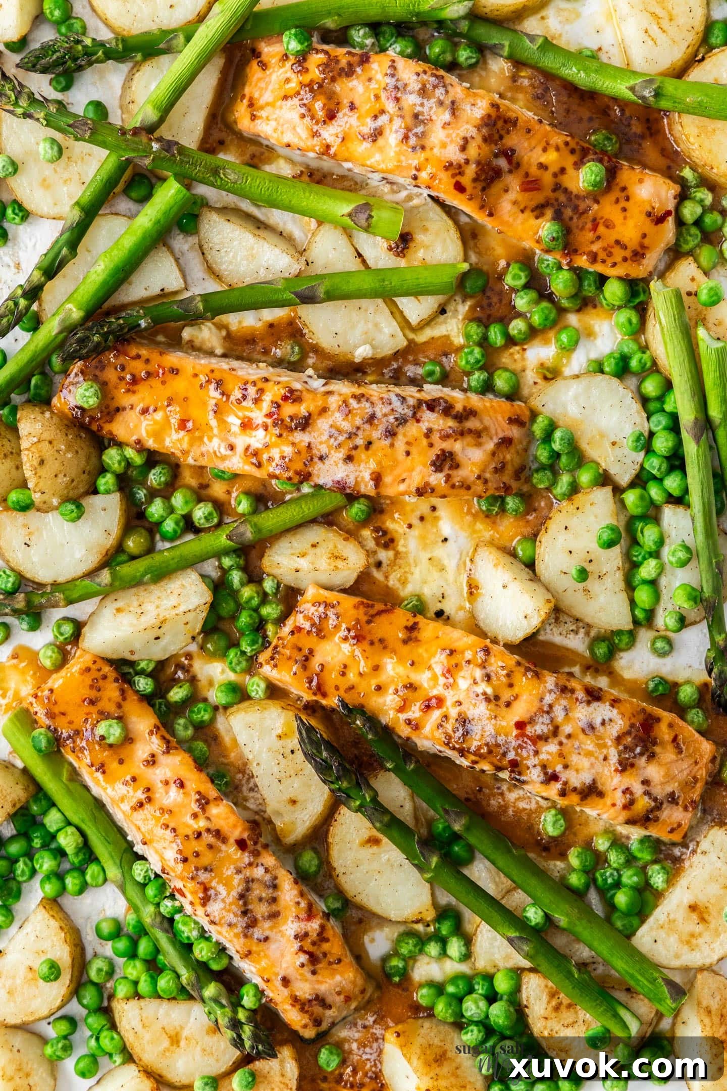 Top down view of honey mustard salmon and veggies on a baking sheet.