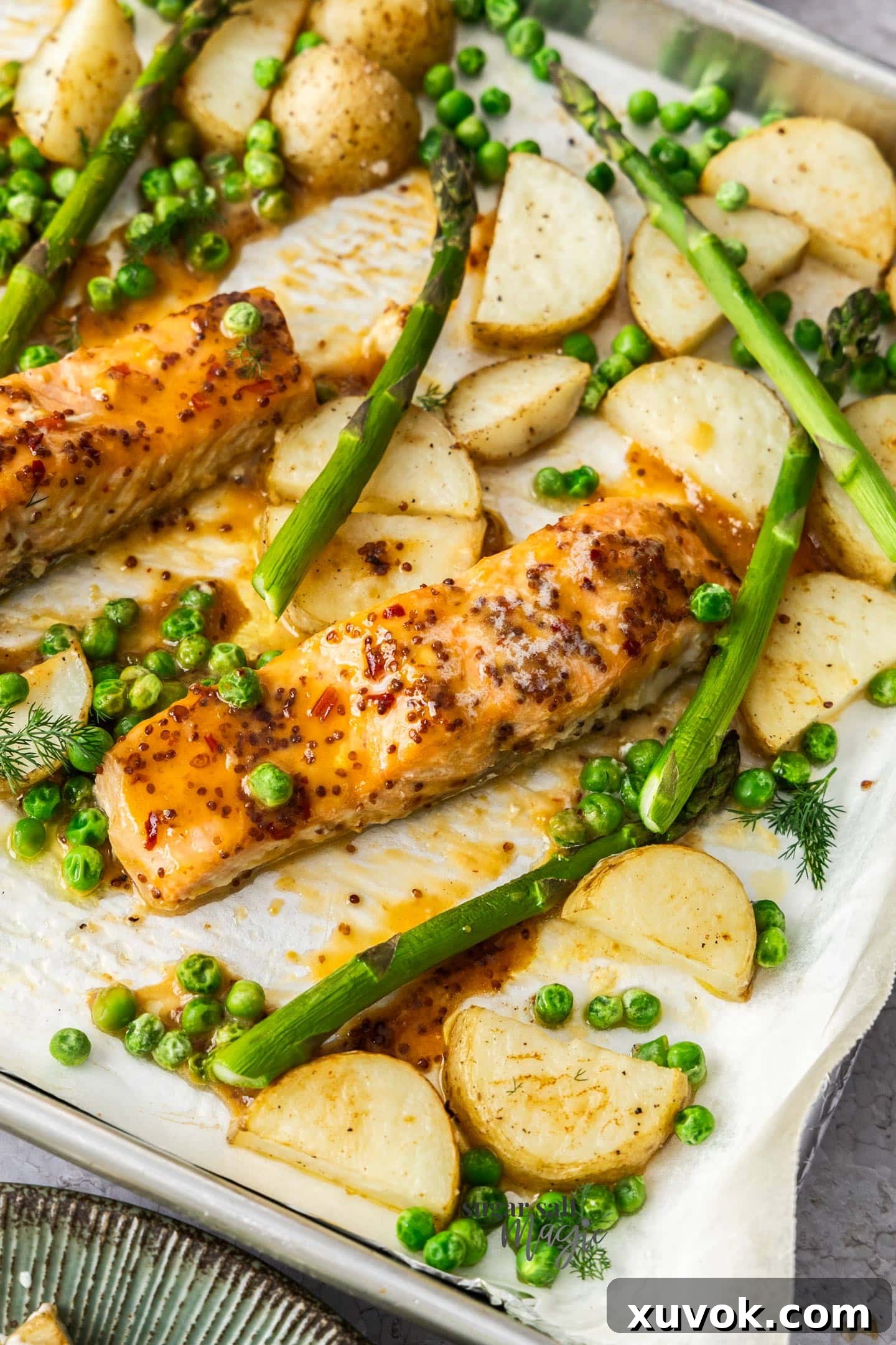 Pieces of honey mustard salmon surrounded by potatoes and asparagus.