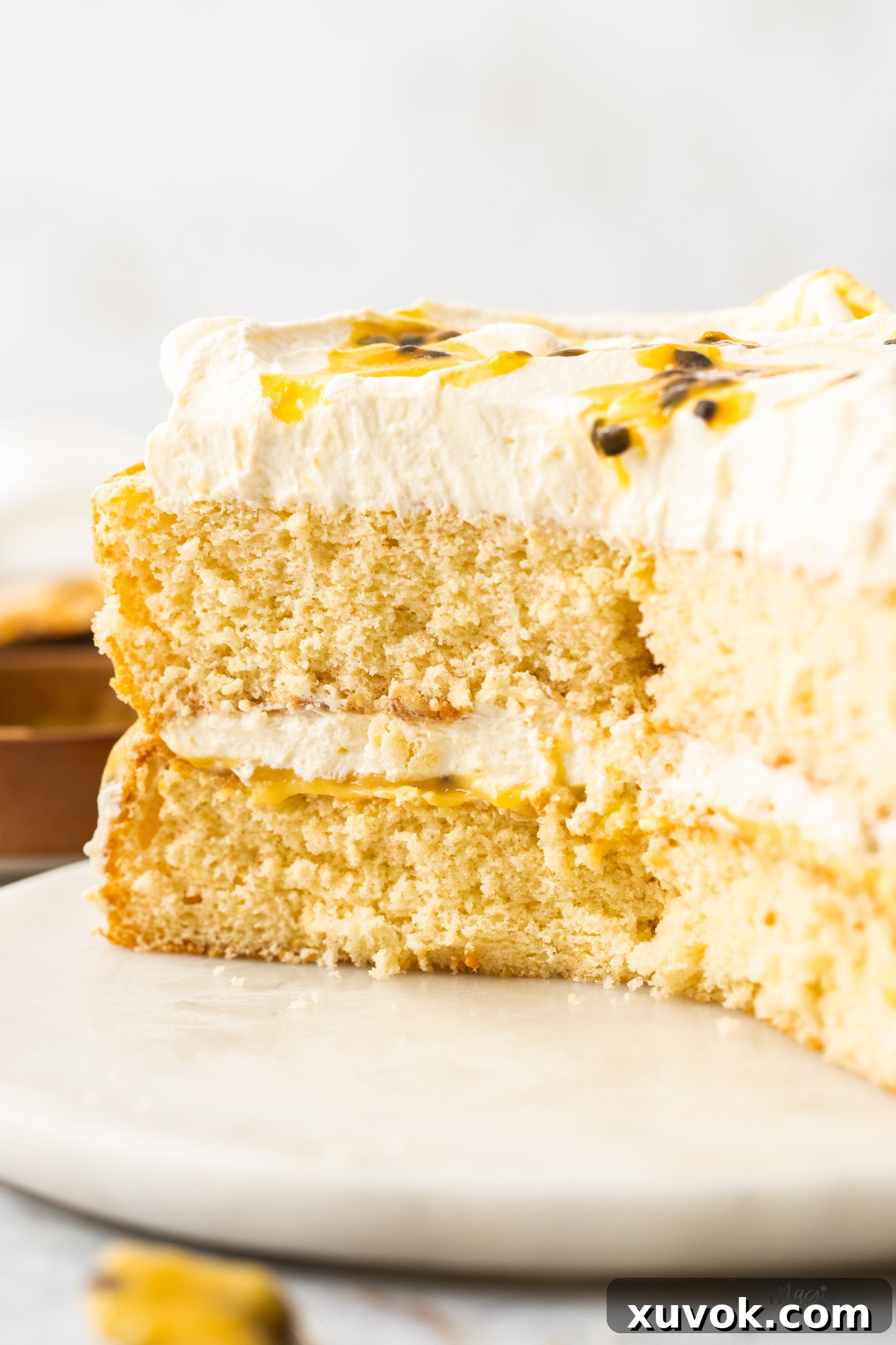 A passionfruit sponge cake, cut open to show the inside texture and layers of cream and curd.