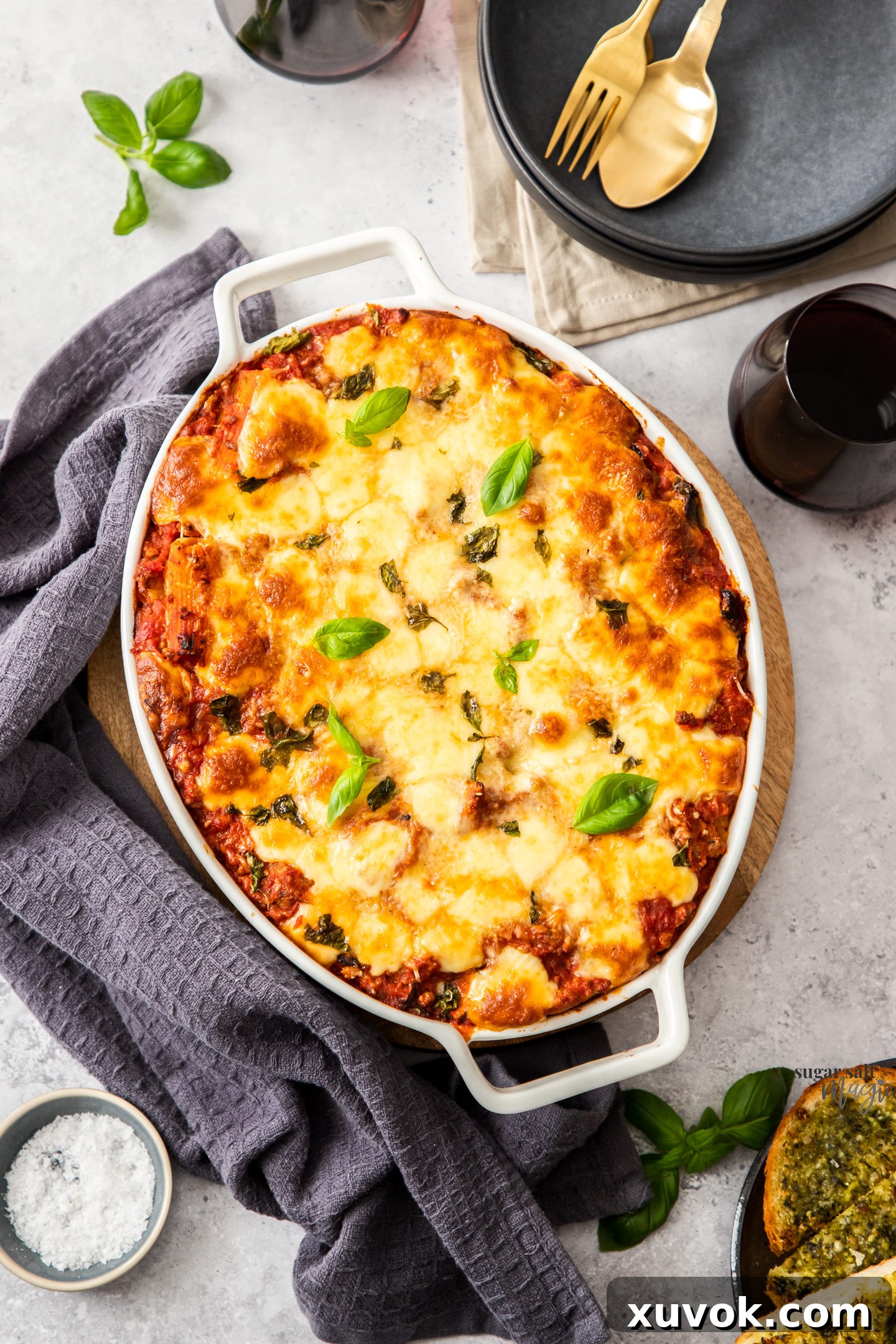 Top down view of an oval casserole dish filled with baked pasta, showcasing a golden-brown cheesy crust and rich tomato meat sauce.