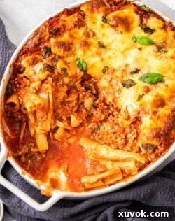 Top down view of rigatoni al forno in a casserole dish with some removed, showcasing its layers.