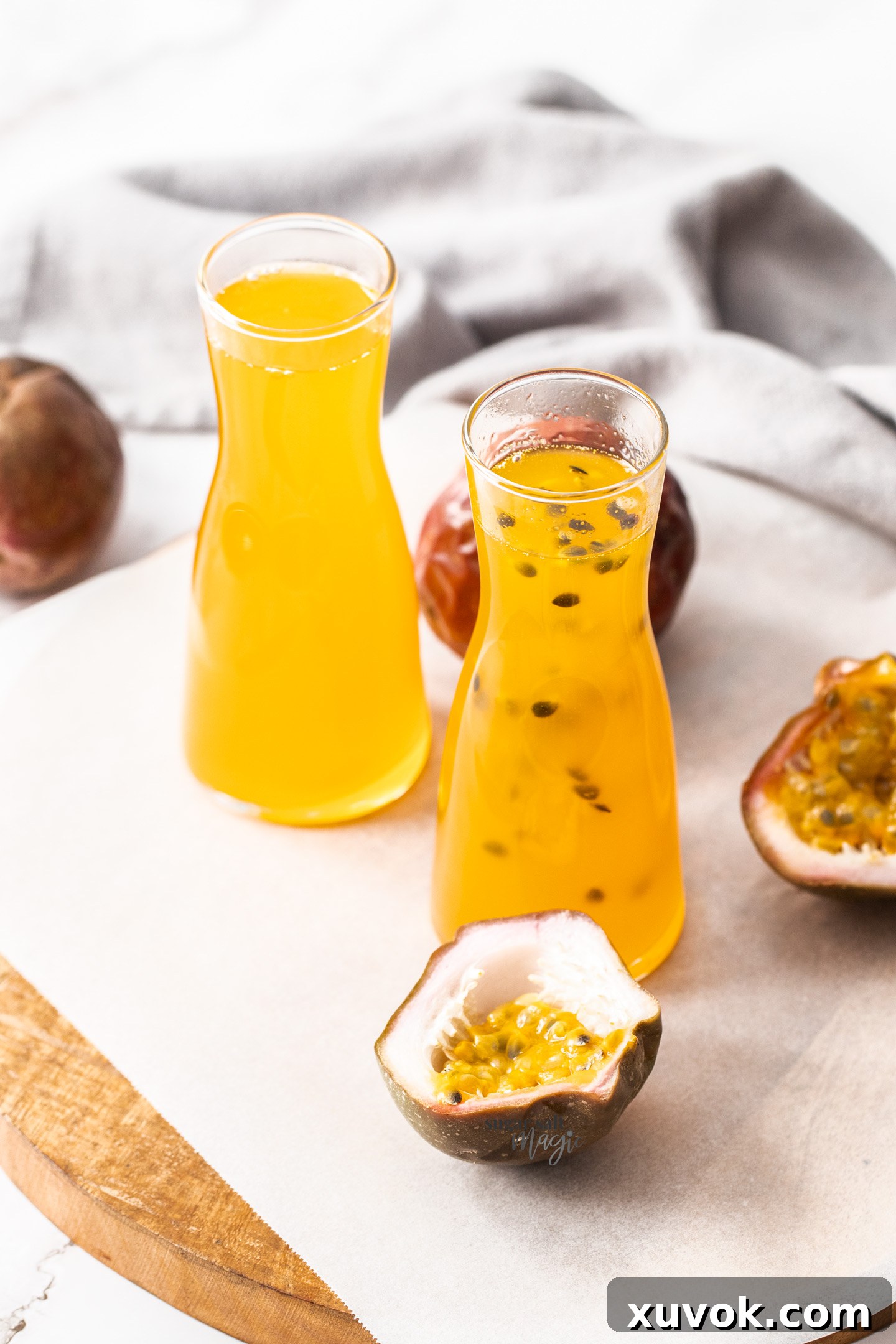 Two bottles of passionfruit syrup surrounded by passionfruits.