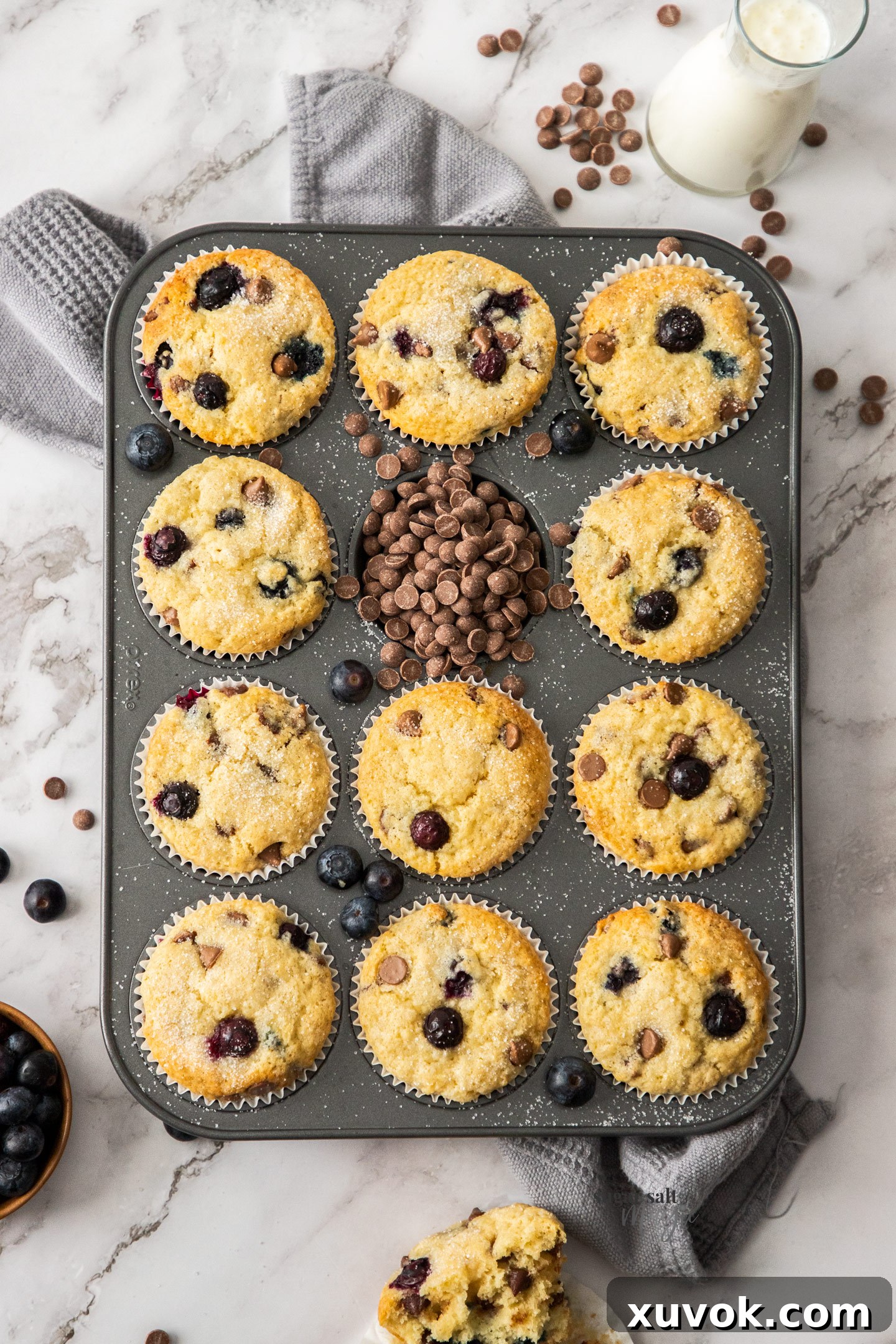 A 12 hole muffin tin filled with baked muffins and chocolate chips.
