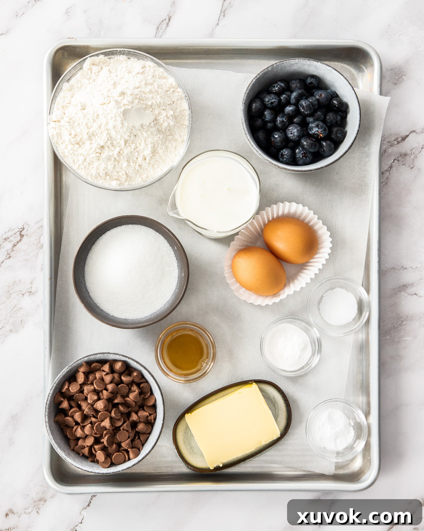 Ingredients for blueberry chocolate chip muffins on a baking tray.