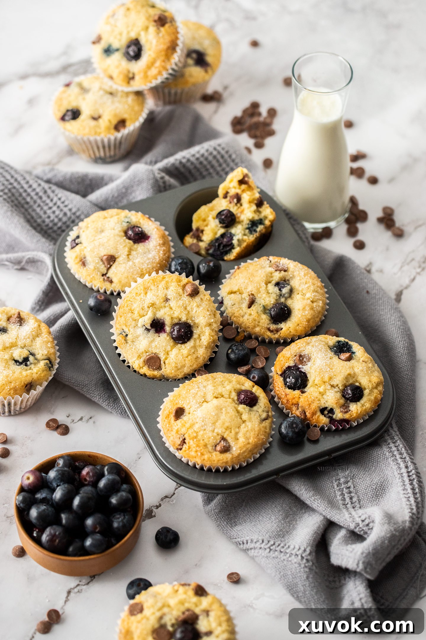 A 6 hole muffin tin with baked blueberry muffins in it.