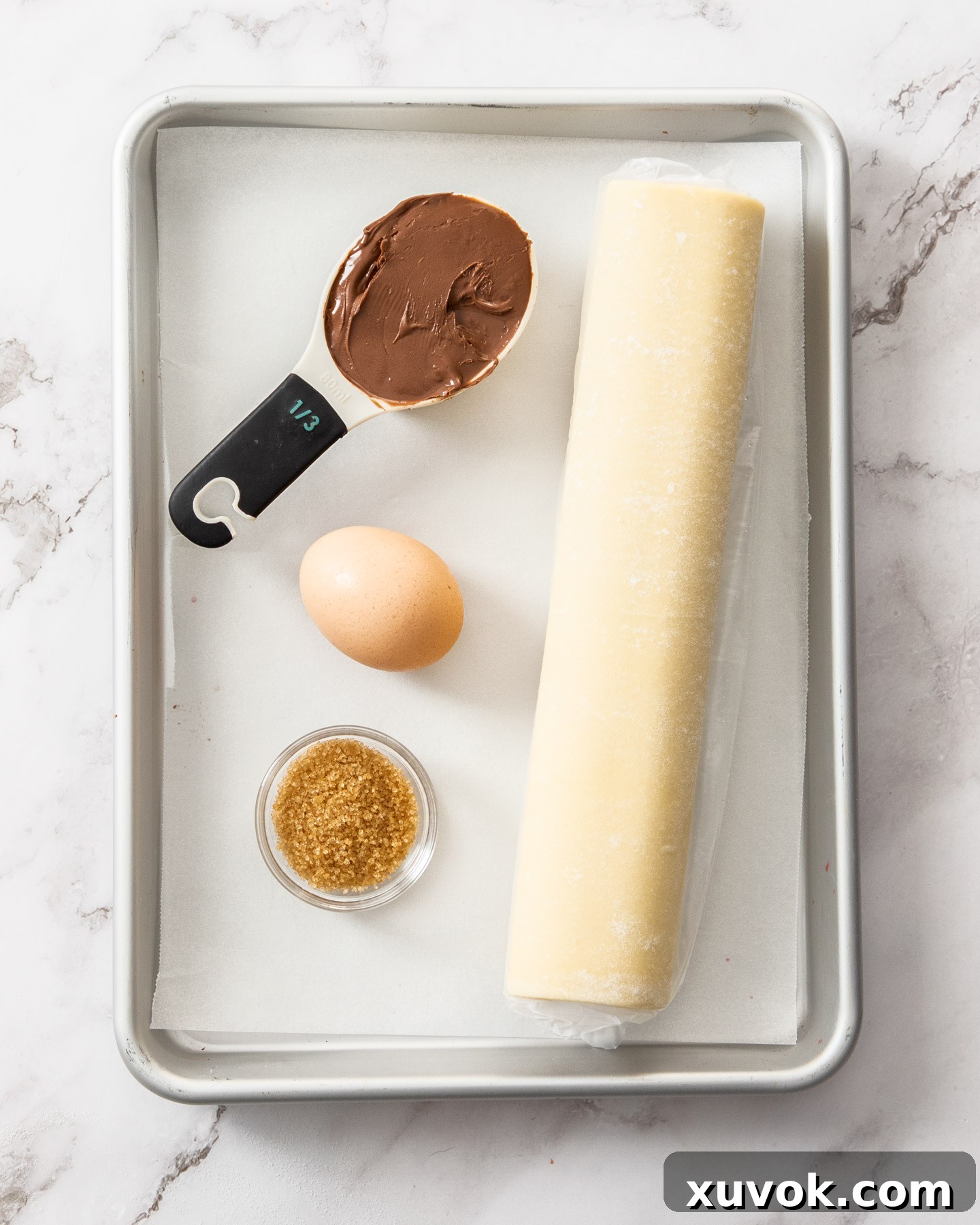 Ingredients for Nutella puff pastry twists laid out on a baking tray, ready for assembly.