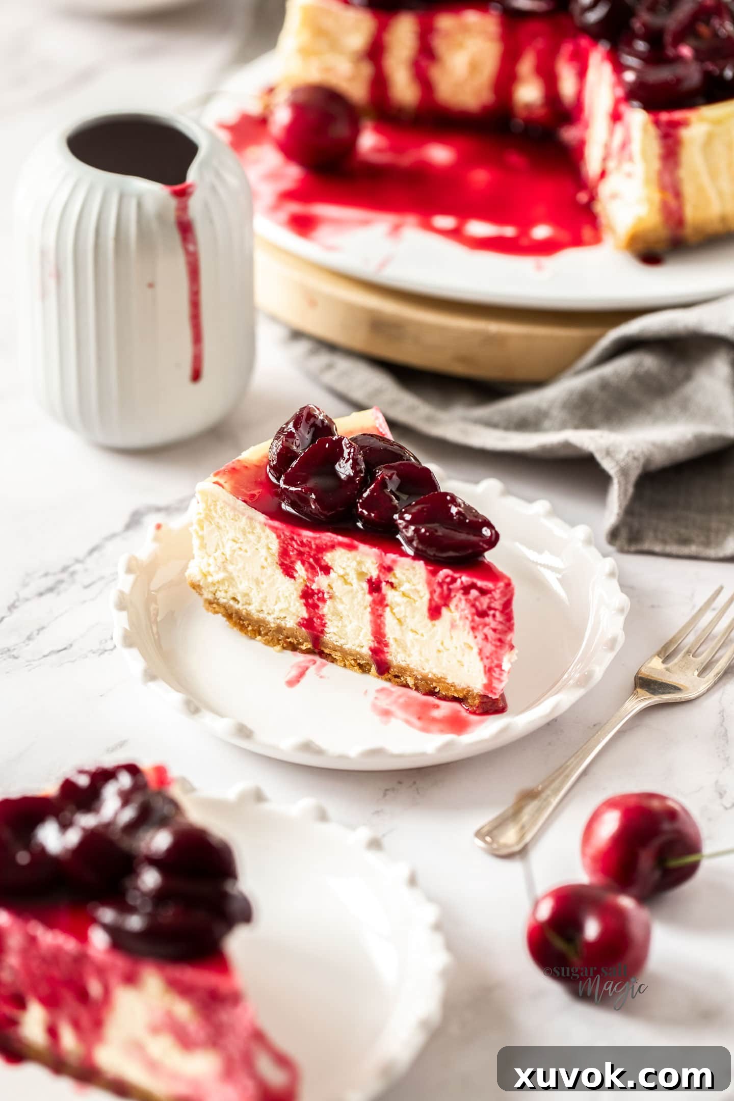 A slice of cherry cheesecake on a white plate with a fork next to it.