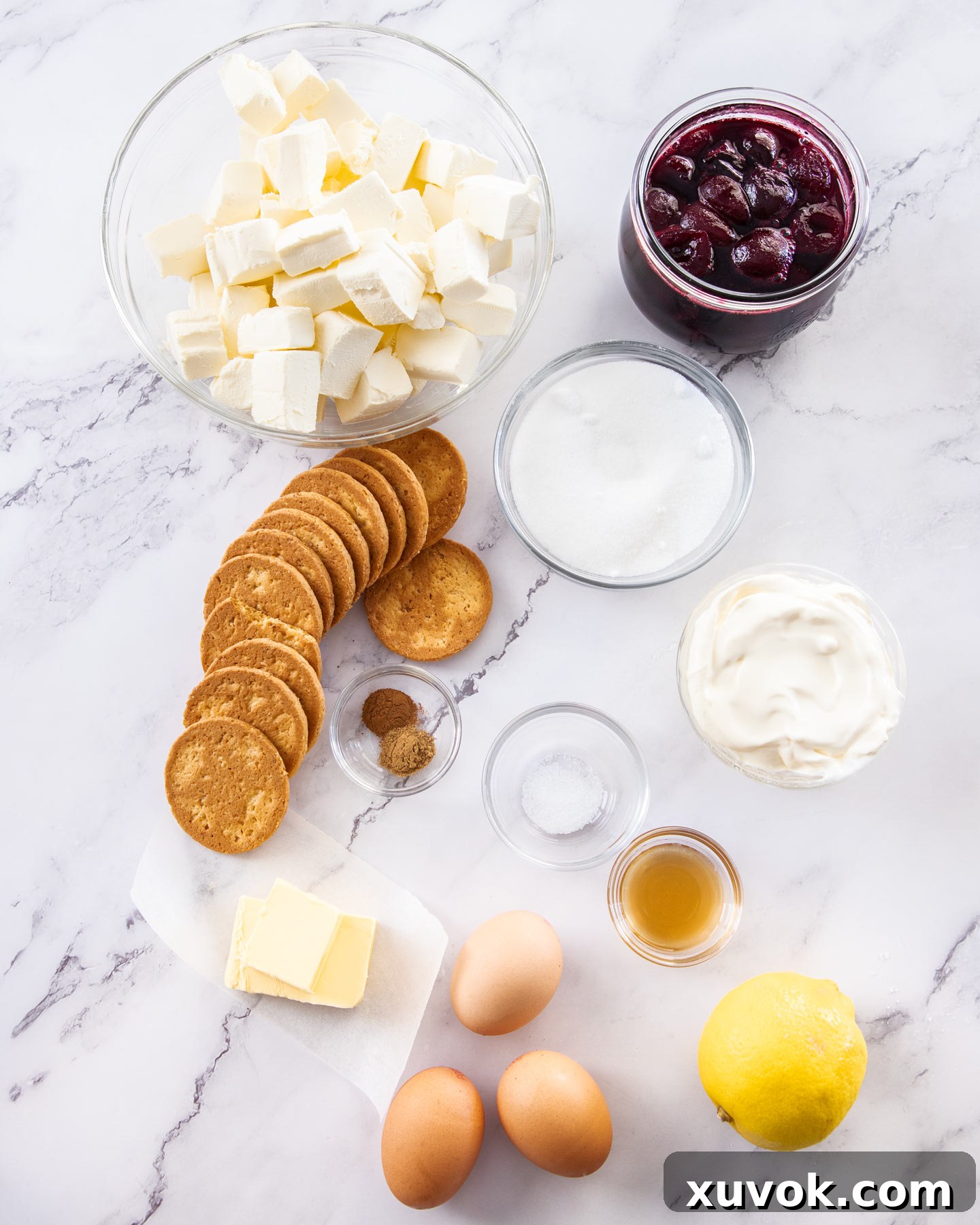 Ingredients for cherry cheesecake on a marble surface.