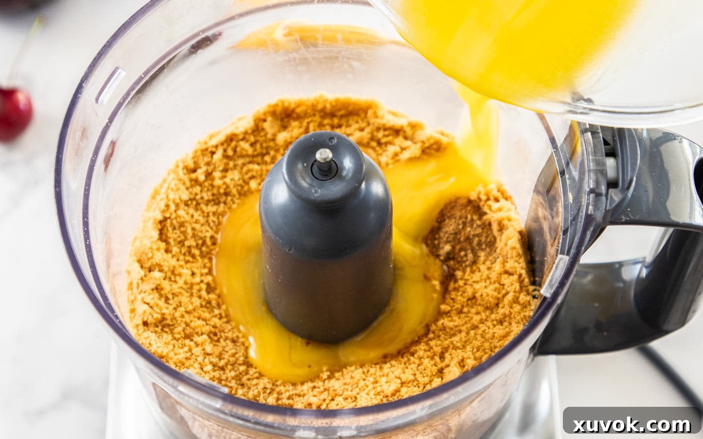 Butter being poured into a food processor with cookie crumbs.