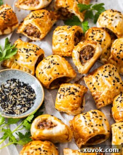 A batch of mini sausage rolls on a sheet of baking paper.