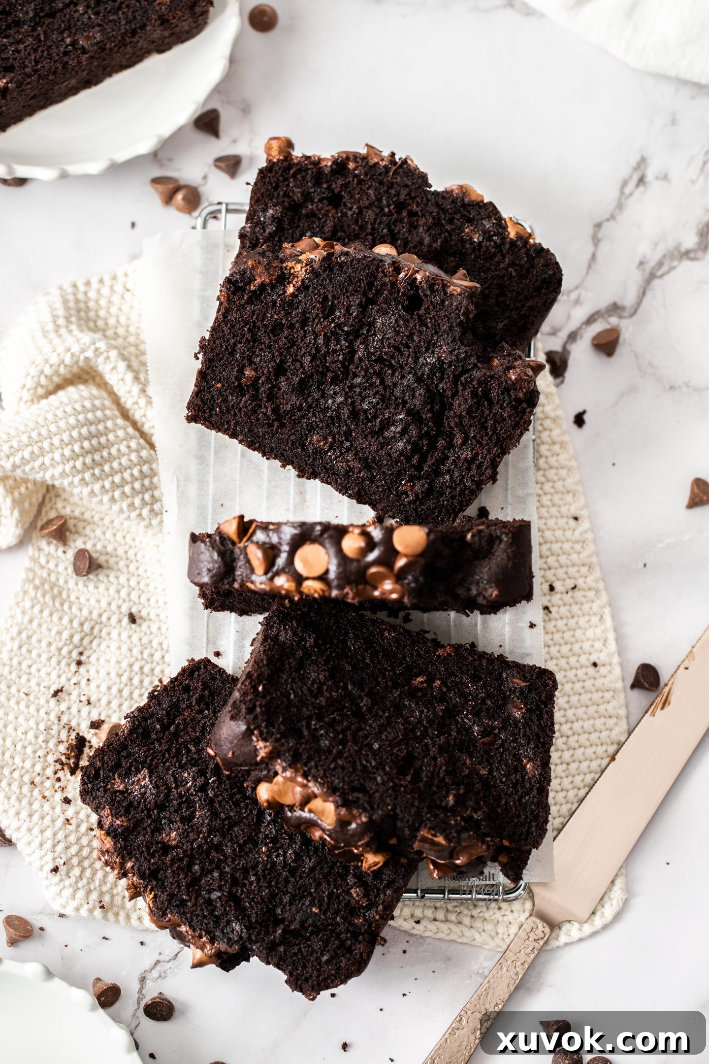Top down view of slices of decadent chocolate zucchini cake cooling on a wire rack, revealing its moist interior and scattered chocolate chips.