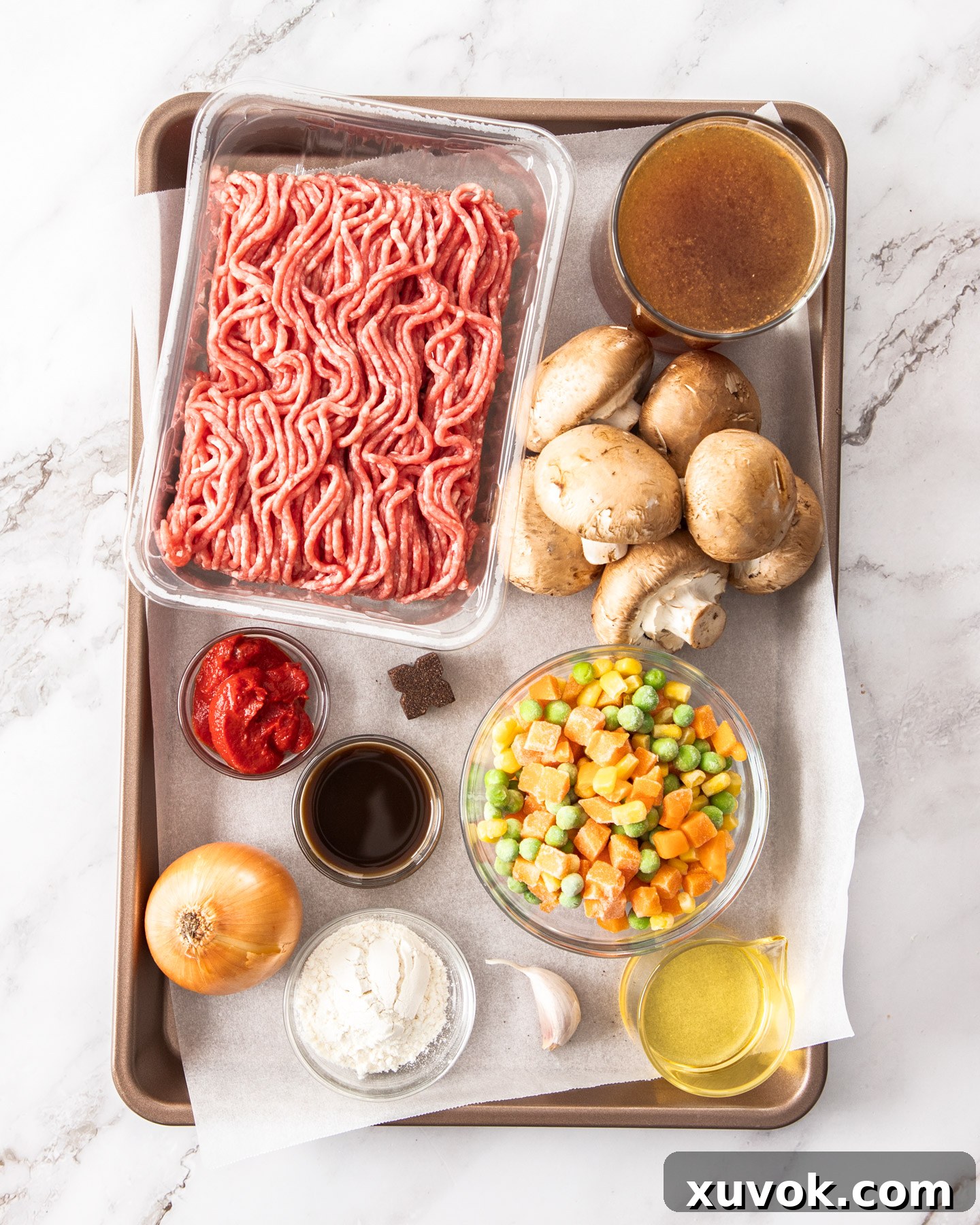 A collection of fresh ingredients for savoury mince laid out on a baking tray.
