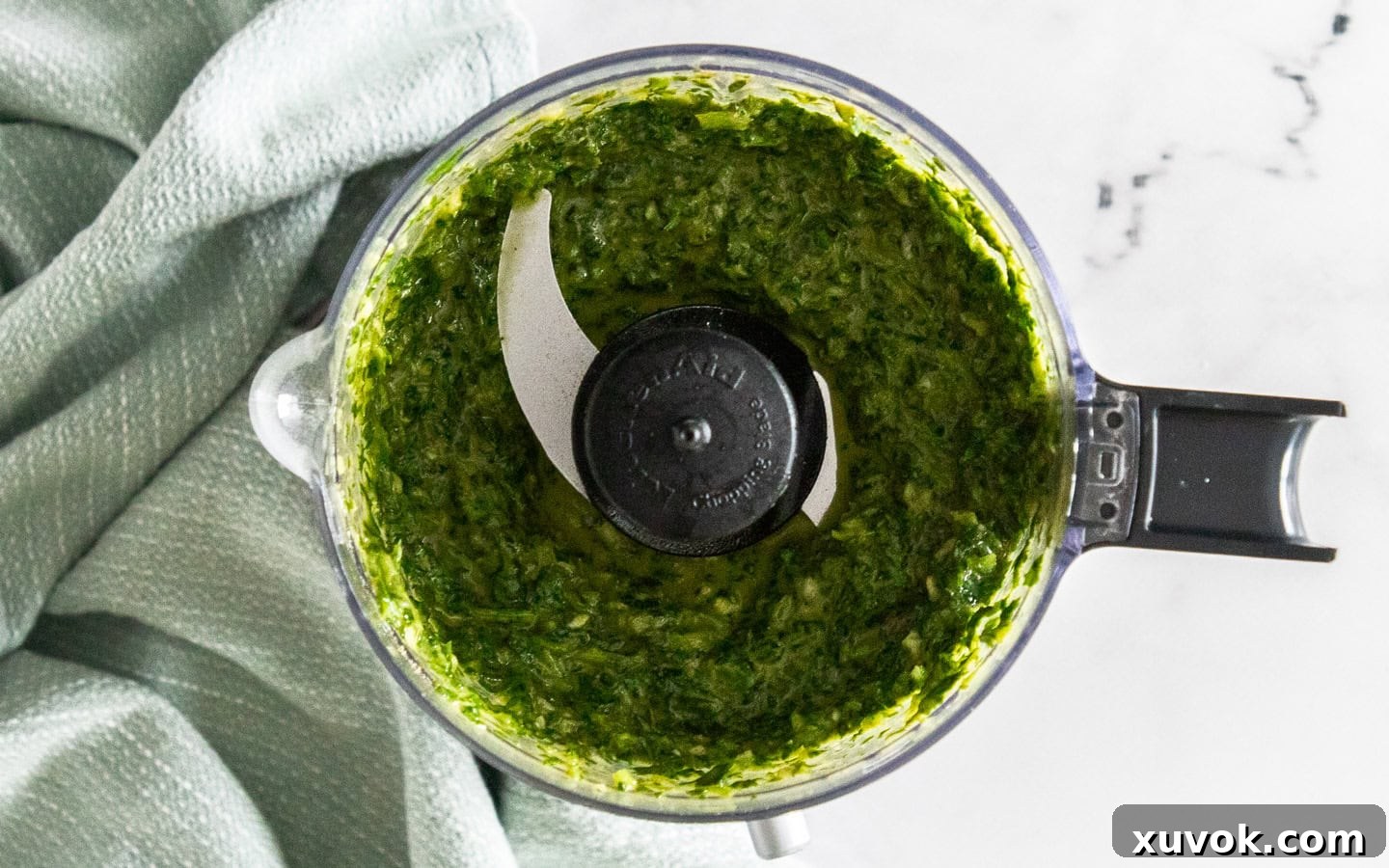The vibrant green mojo verde ingredients expertly blended together in a mini food chopper, showing the smooth consistency.