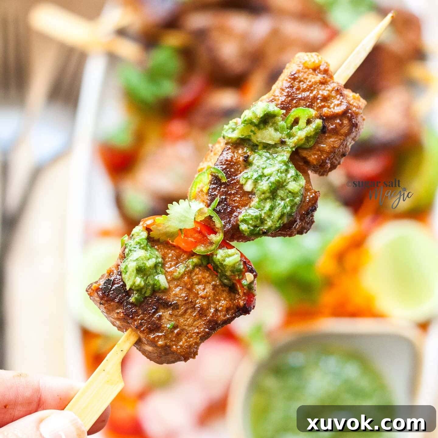 A perfectly grilled beef shish kebab, beautifully garnished with a generous drizzle of vibrant green mojo verde sauce, highlighting its fresh appeal.