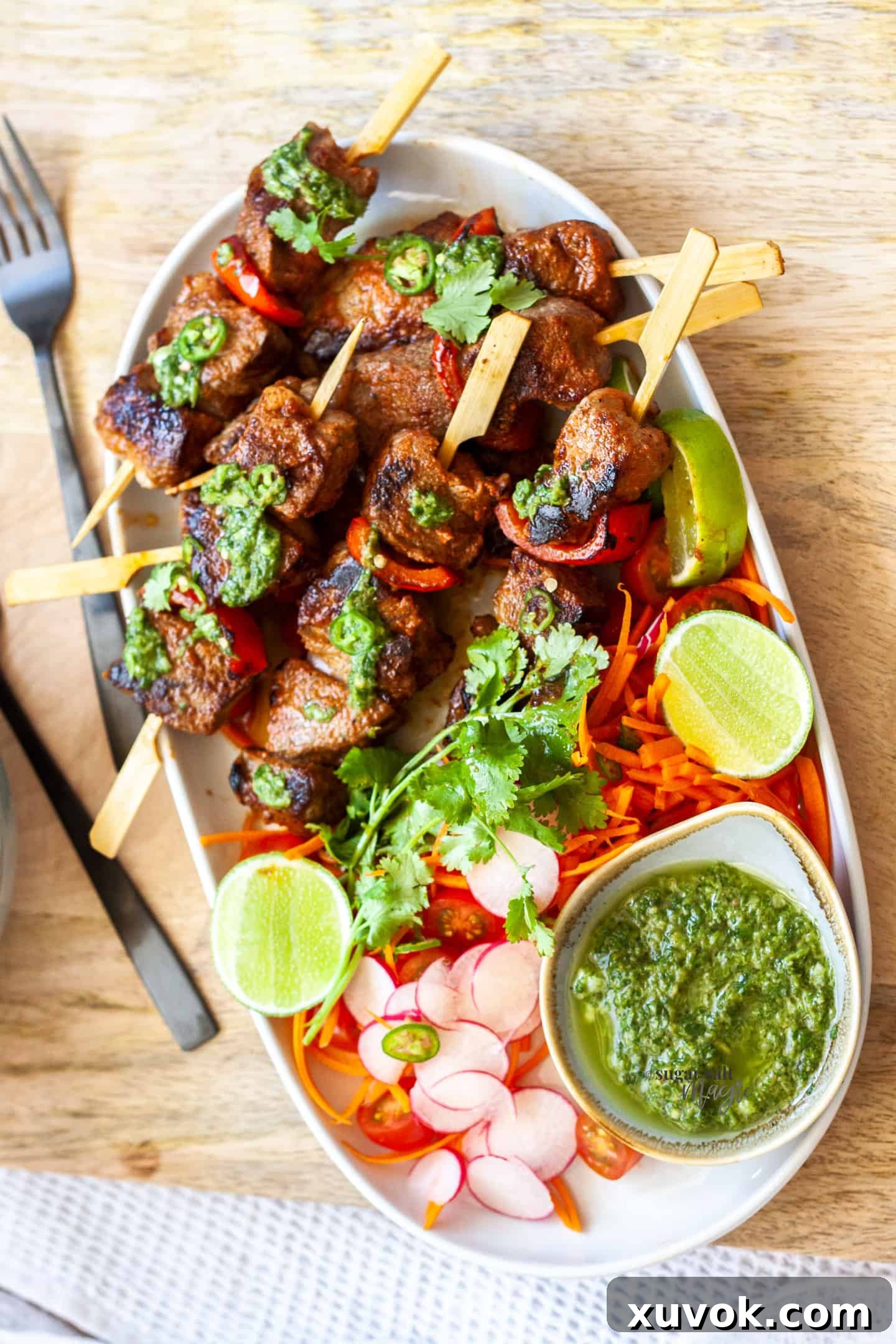 An oval dish on an angle filled with a fresh salad and juicy steak kabobs, perfectly grilled.