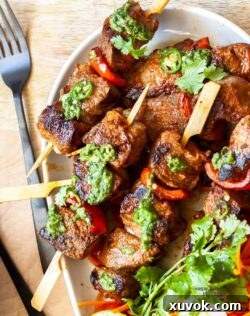 Top down view of perfectly grilled steak kabobs with a vibrant green sauce, ready to be served.