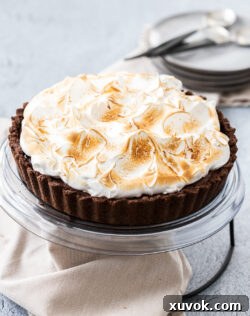 A whole, beautifully presented no-bake chocolate meringue pie on a cake platter, ready to be served.