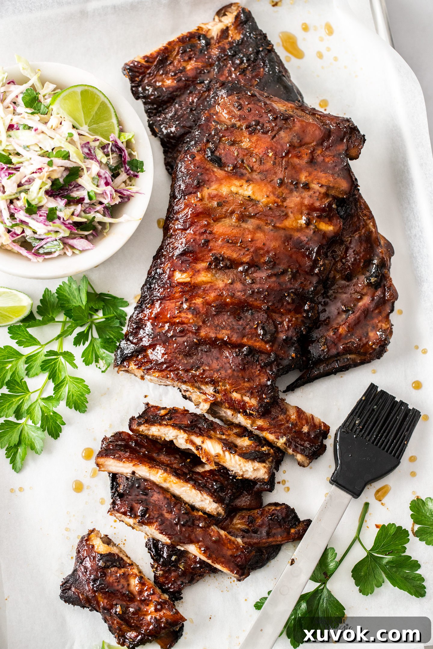 A top-down view of glazed, baked honey garlic pork ribs on a baking tray, ready to be served. The ribs are dark, sticky, and look incredibly tender, promising a delightful fall-off-the-bone experience.