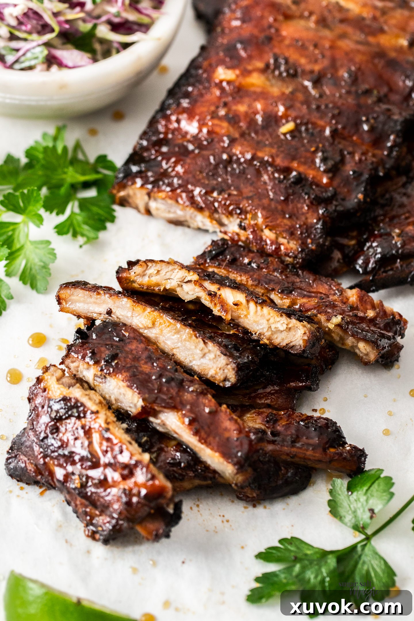 A baking tray filled with perfectly cooked and glazed honey garlic pork ribs, showcasing their deep caramelized color and sticky texture, ready for serving.