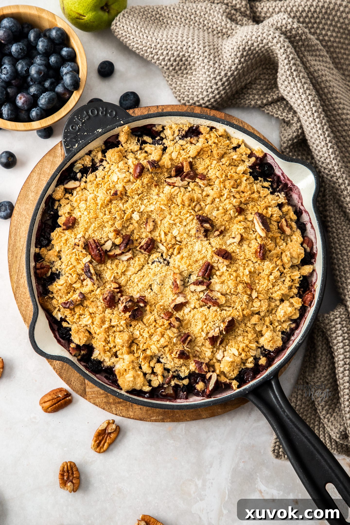 Top down view of the golden crumble topping on a blueberry and pear crumble, showing its crisp texture.