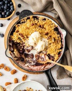 A skillet filled with a freshly baked blueberry and pear crumble, golden and bubbly.