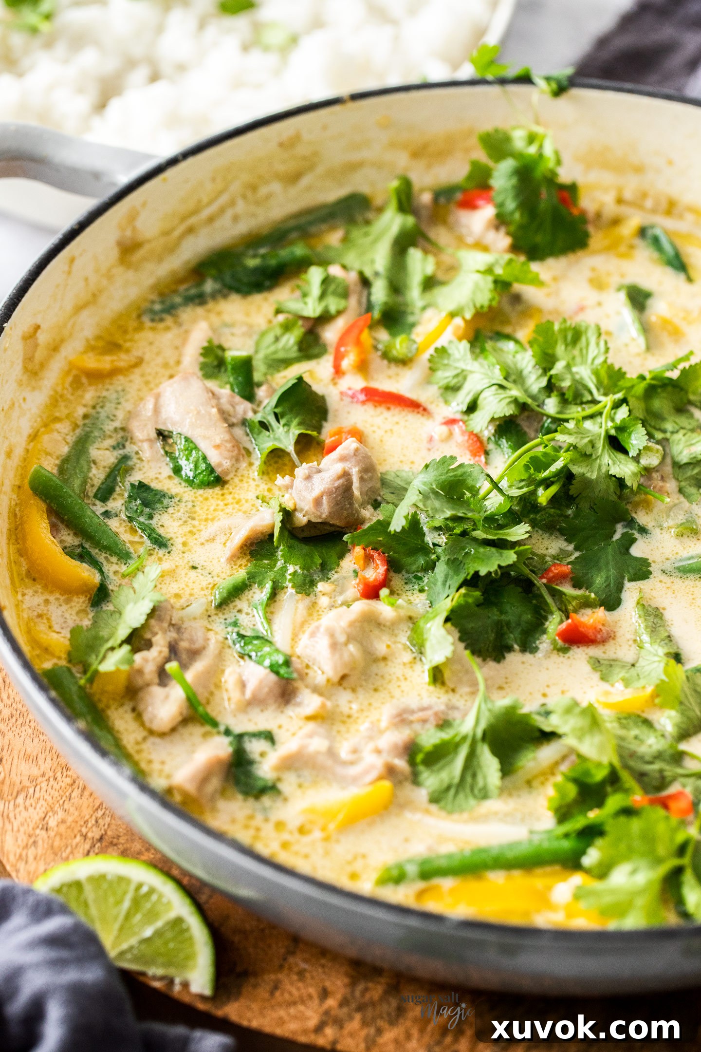 Green chicken curry in a pan topped with coriander. A bubbling pan of vibrant Thai Green Chicken Curry, freshly cooked and garnished with bright green coriander leaves, ready to be served. The rich, creamy sauce and tender chicken pieces are clearly visible, promising a delicious and aromatic meal.