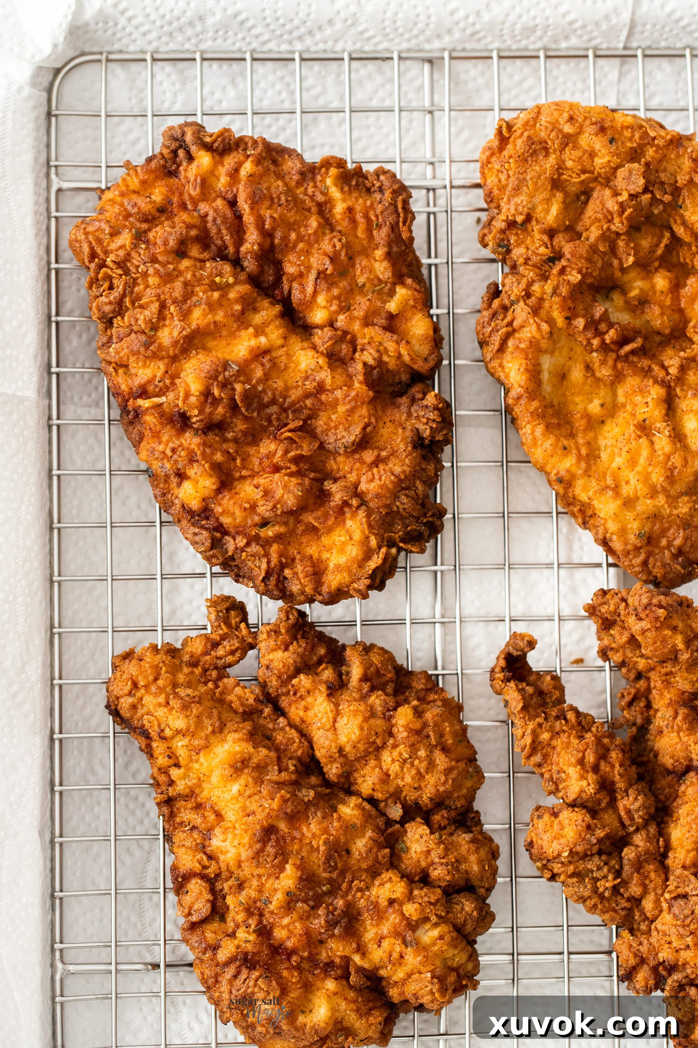 Crispy fried chicken breasts resting on a wire rack.