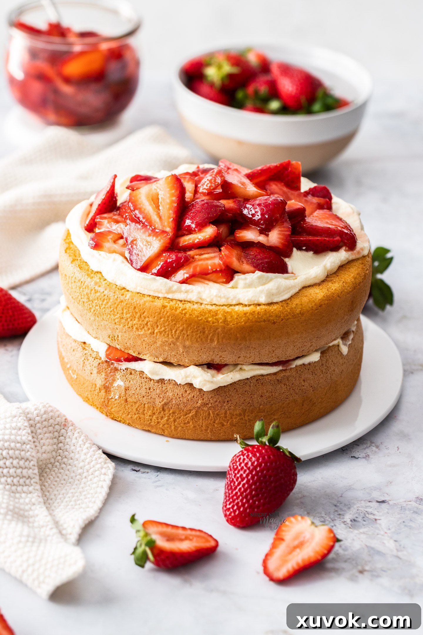 A beautifully assembled strawberry sponge cake sitting gracefully on a cake platter.