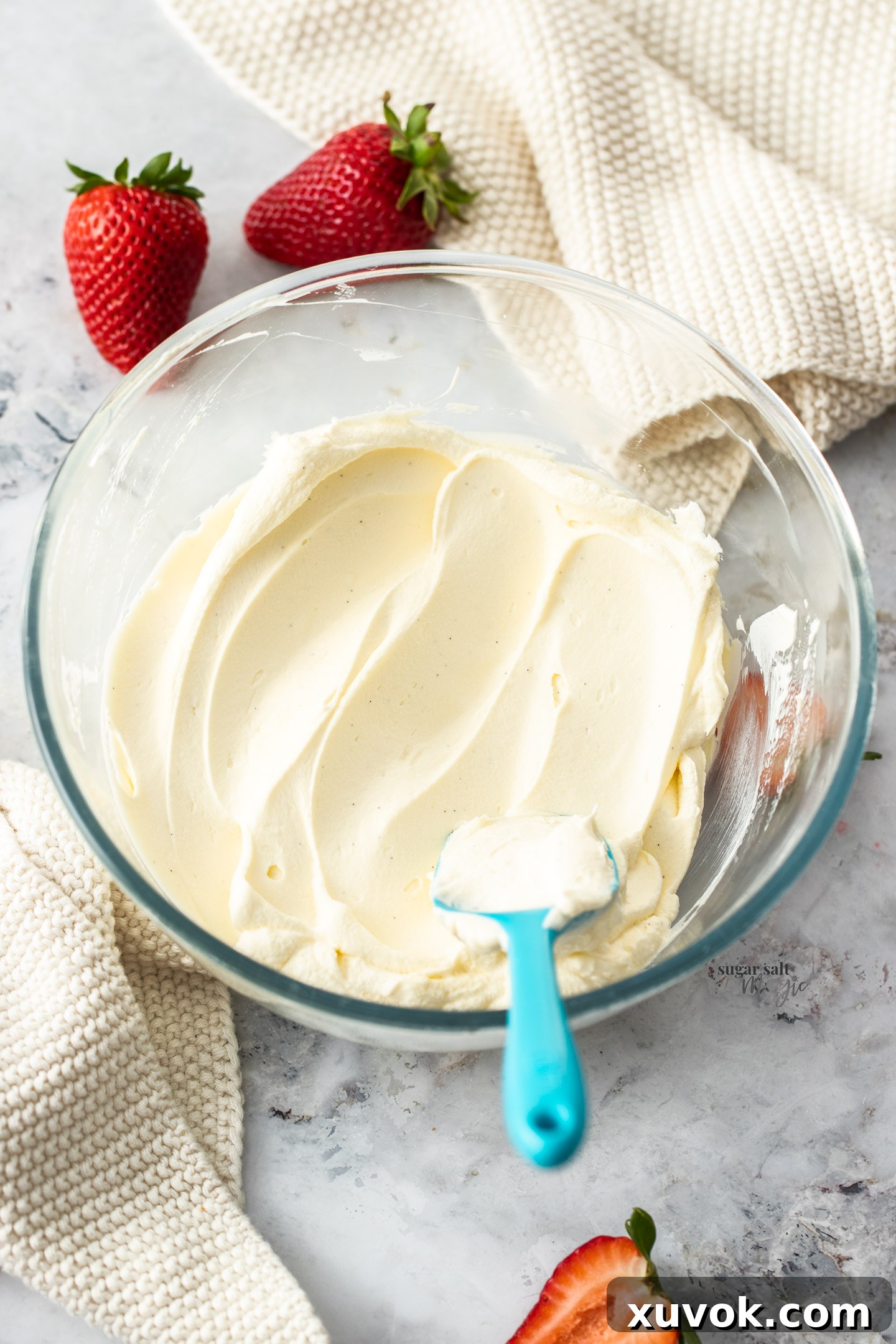 Chantilly cream in a glass bowl, elegantly presented alongside fresh strawberries.