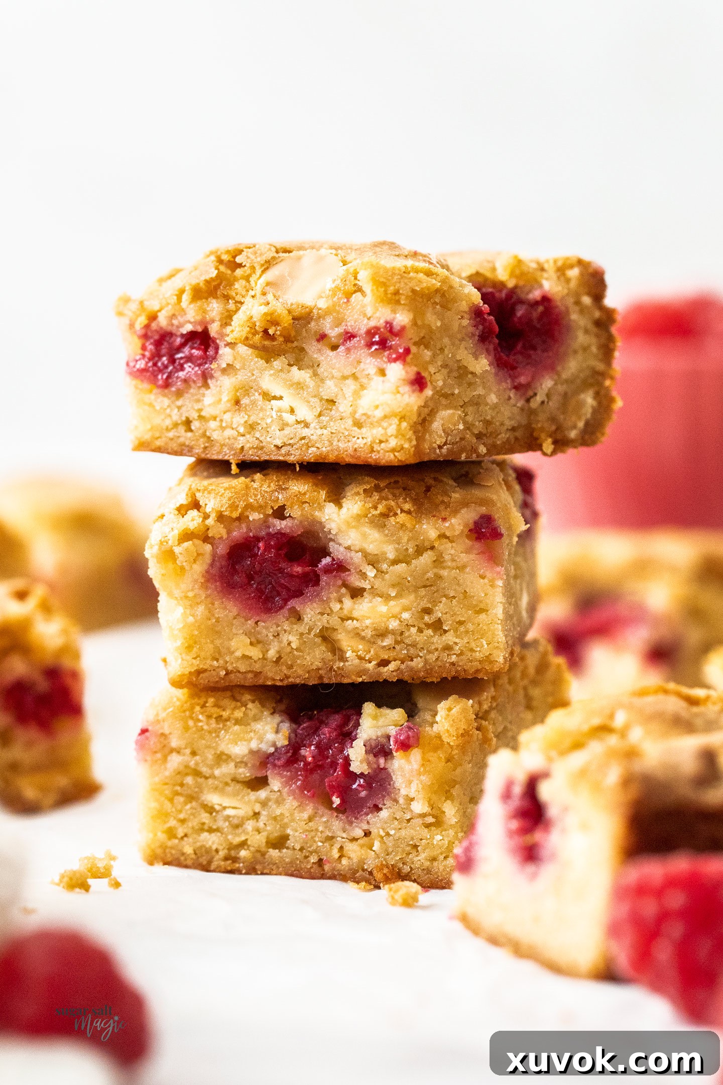 A stack of three decadent white chocolate raspberry blondies, showcasing their fudgy texture and vibrant raspberry inclusions.