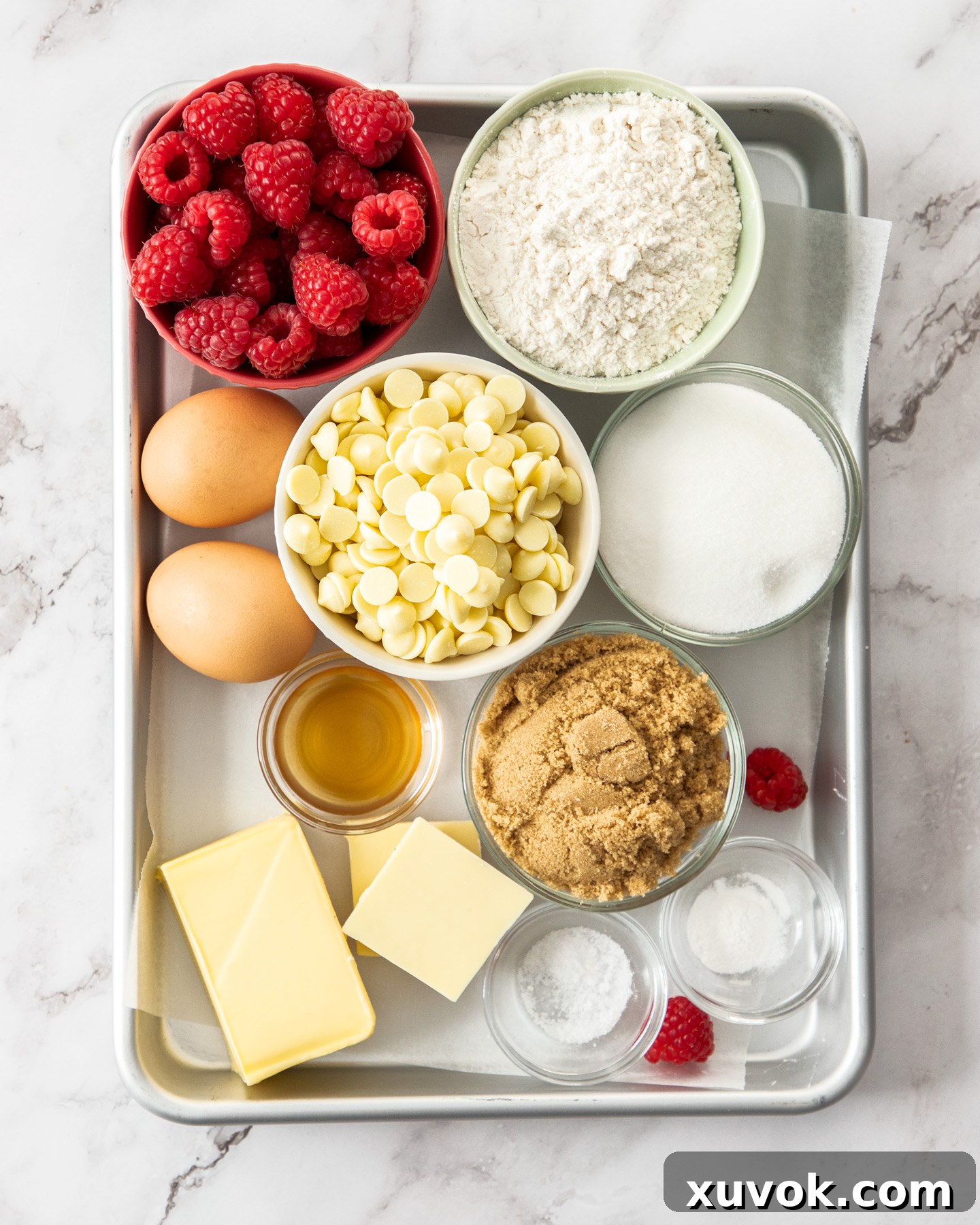 A flat lay of all the essential ingredients for making white chocolate and raspberry blondies, neatly arranged.