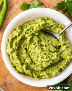 Closeup of vibrant homemade Thai green curry paste in a marble bowl, showcasing its smooth texture.