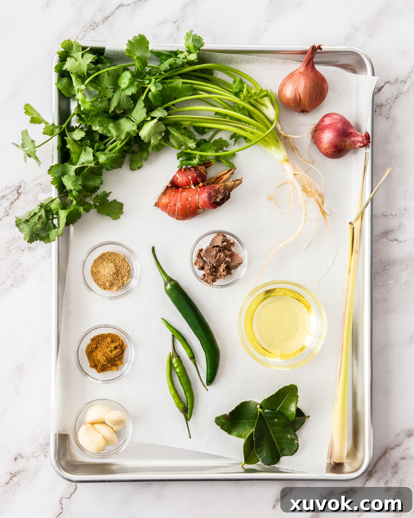 A collection of fresh ingredients meticulously laid out on a baking tray, ready for making Thai green curry paste.