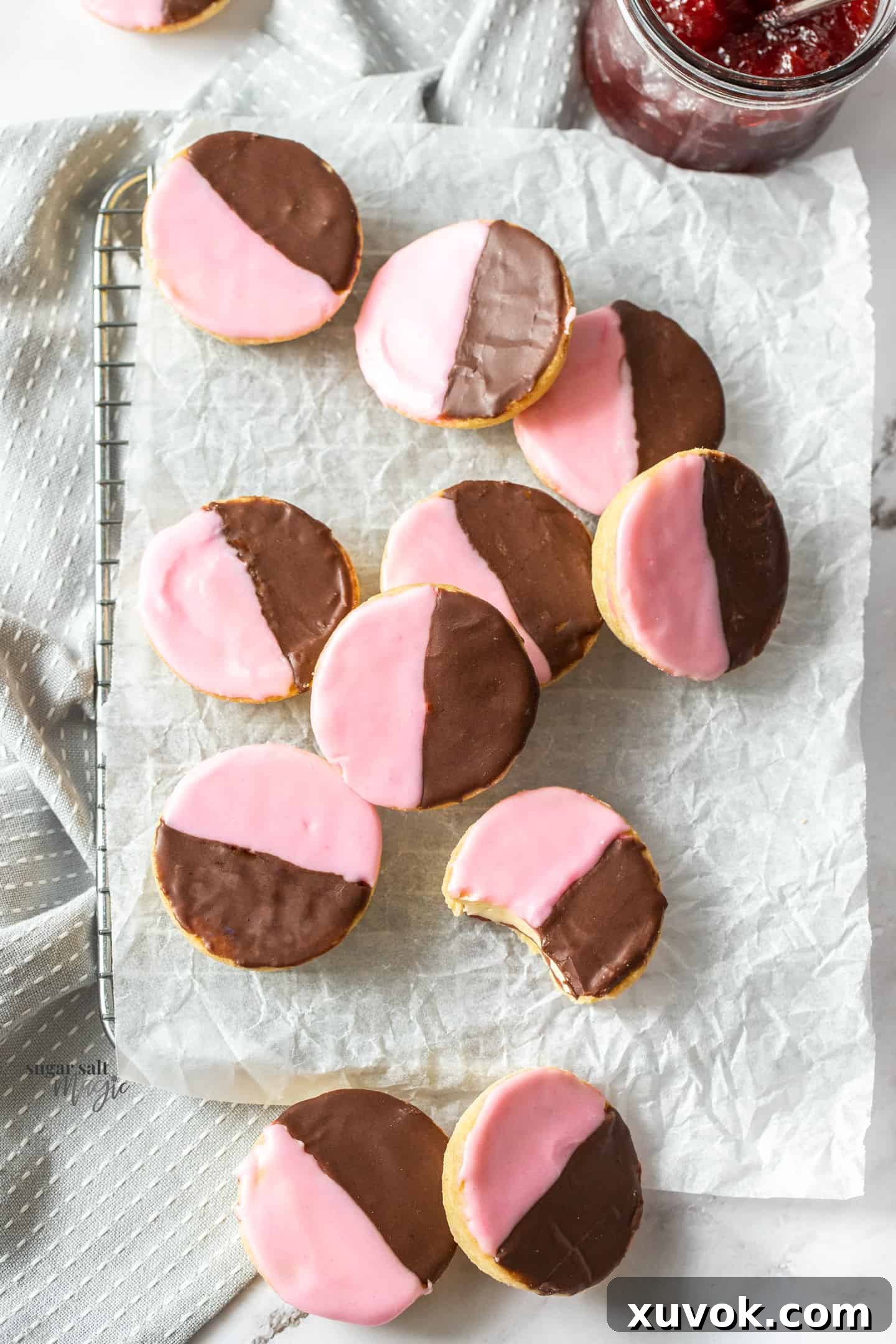 A batch of traditional Neenish tarts arranged neatly on a sheet of baking paper, showcasing their distinct two-tone icing and golden pastry crusts. They are small, round, and perfect for an afternoon treat.