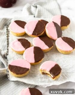 A batch of neenish tarts on a sheet of baking paper over a wire rack, perfectly showcasing their golden crusts and two-tone icing. Each tart is a testament to traditional Australian baking.