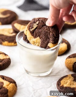 A marble cookie being dipped into milk, highlighting its enticing swirl.