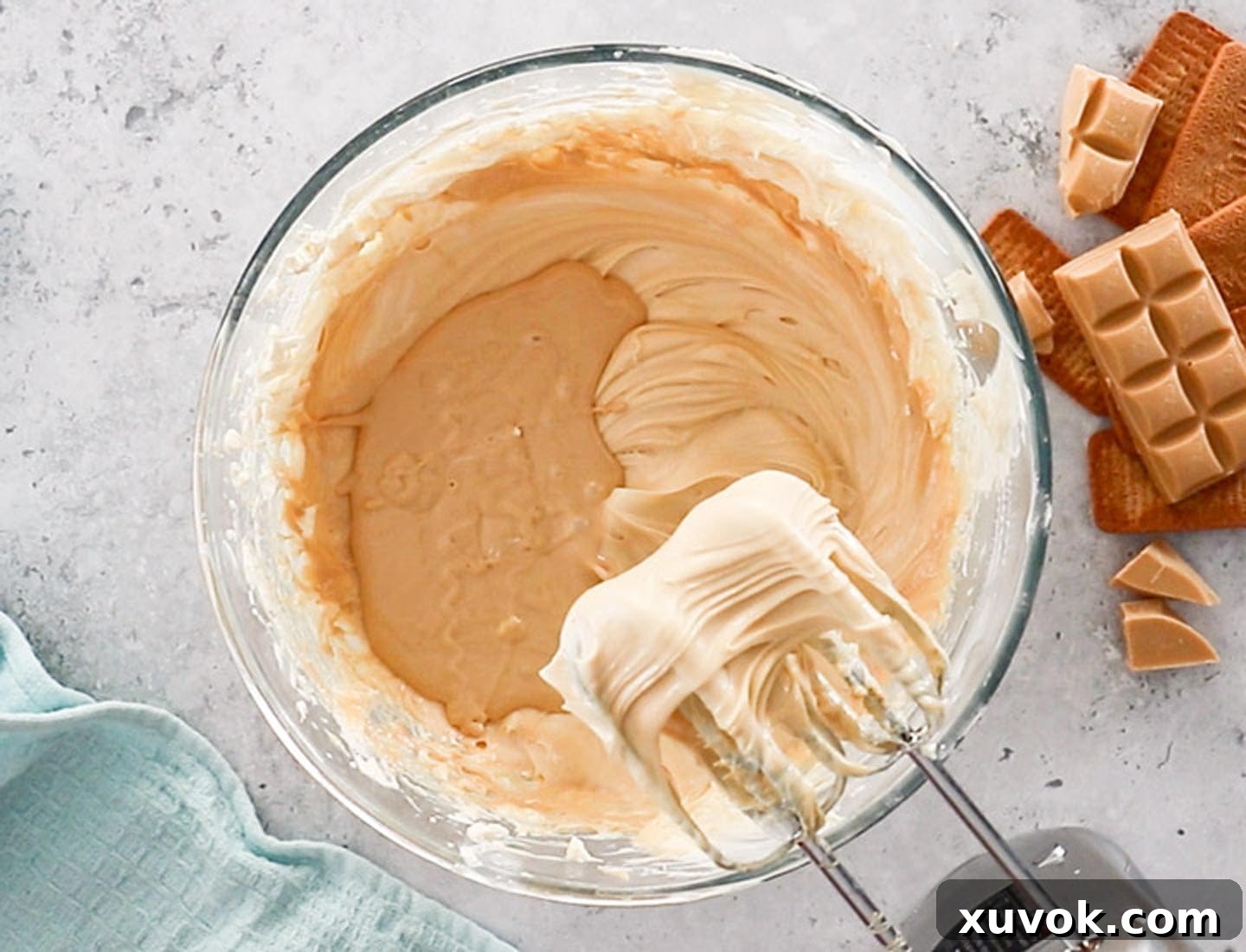 Melted Caramilk chocolate being gently mixed into the creamy cheesecake batter, creating a harmonious blend of flavors.