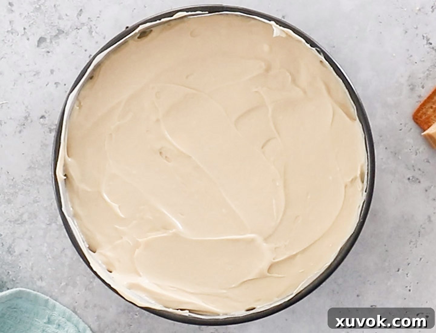 The smooth and creamy Caramilk cheesecake filling expertly spread over the cookie base in a springform pan, ready for chilling.