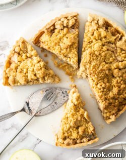 A top-down view of a golden brown apple crumble tart, perfectly sliced into wedges, showcasing its crispy topping and tender apple filling, ready to be served.