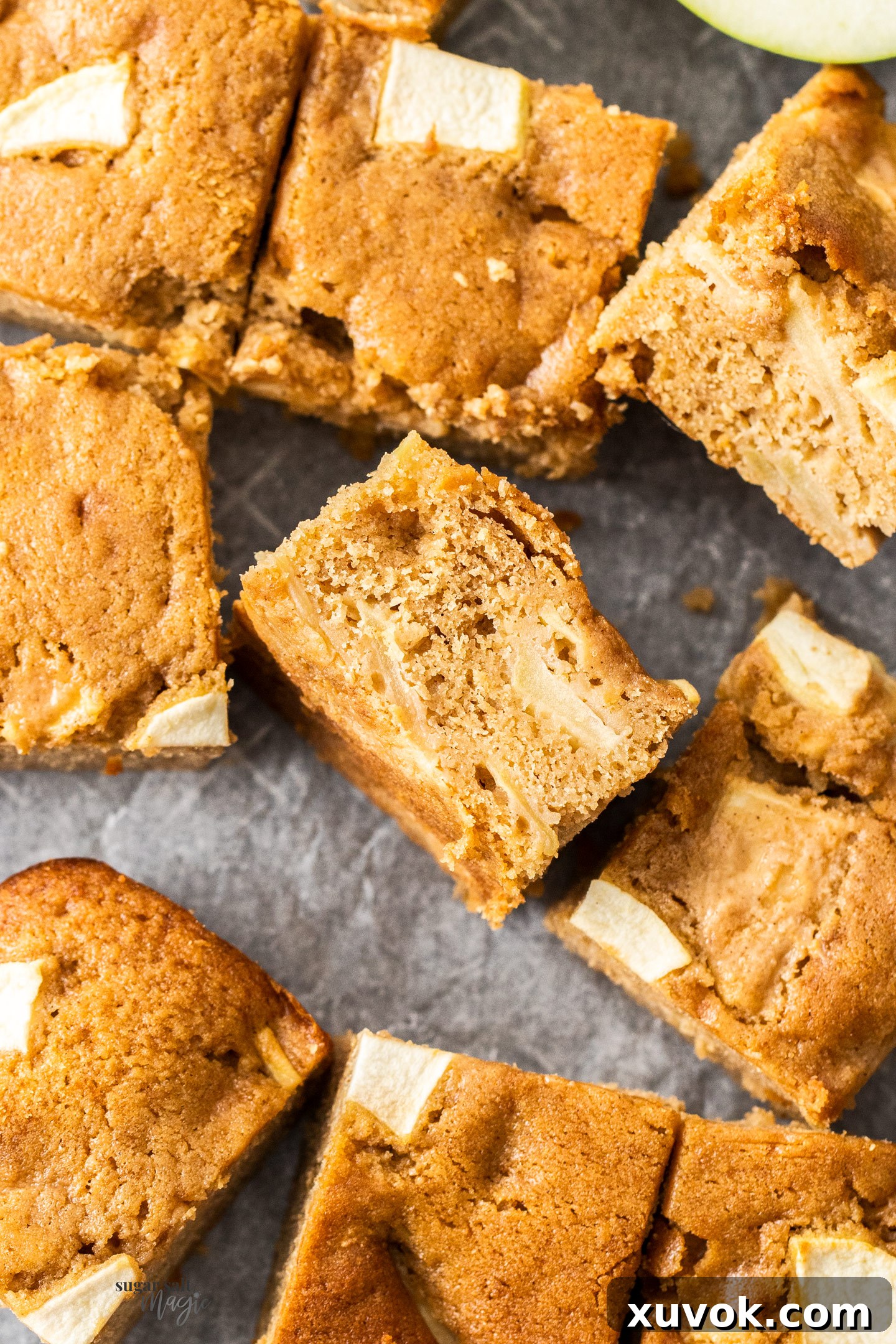 A close-up view of a baked apple tray bake, showing its moist, tender interior with visible chunks of cinnamon-spiced apple.