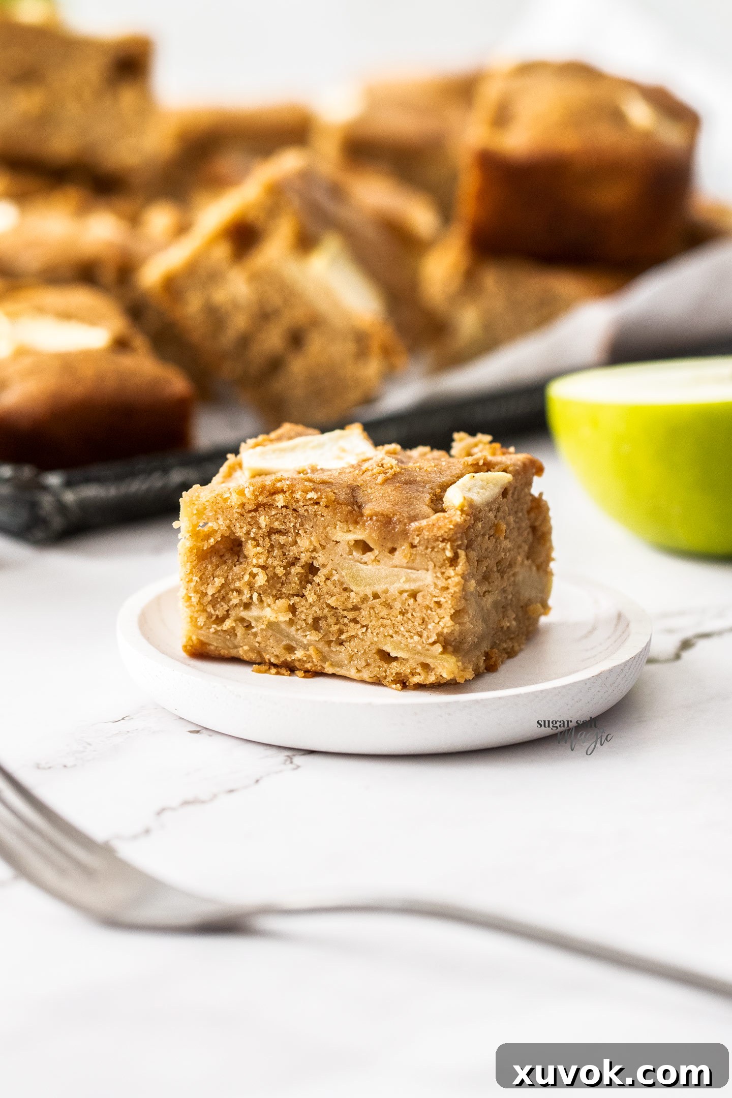 A perfectly portioned slice of apple tray bake resting on a delicate small dessert plate, ready to be enjoyed.