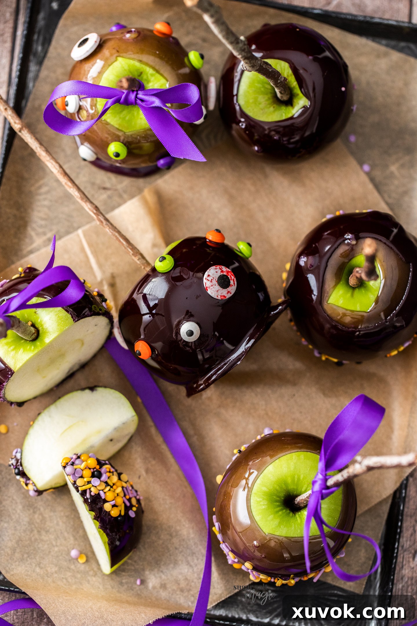 A candy apple decorated with candy eyes laying on it's side.
