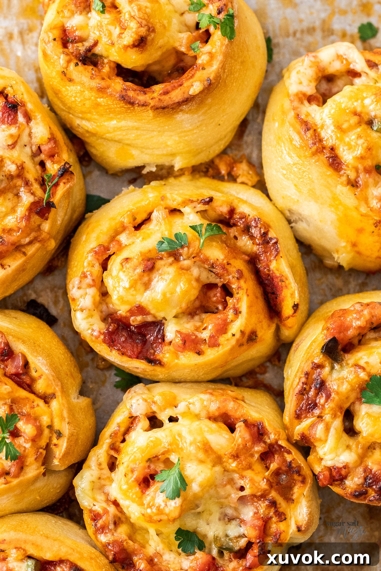 A close-up, top-down view of a single, perfectly baked pizza scroll, showing its golden crust and the enticing swirl of cheese and toppings.