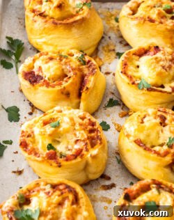 Close up of 8 pizza scrolls on a baking tray, showing their golden tops and melted cheese.