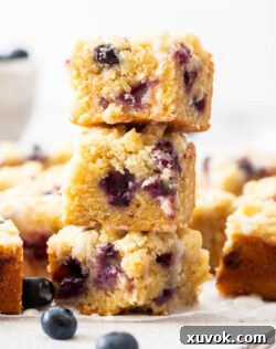 A stack of 3 blueberry blondies, highlighting their fudgy texture and delicious crumb.