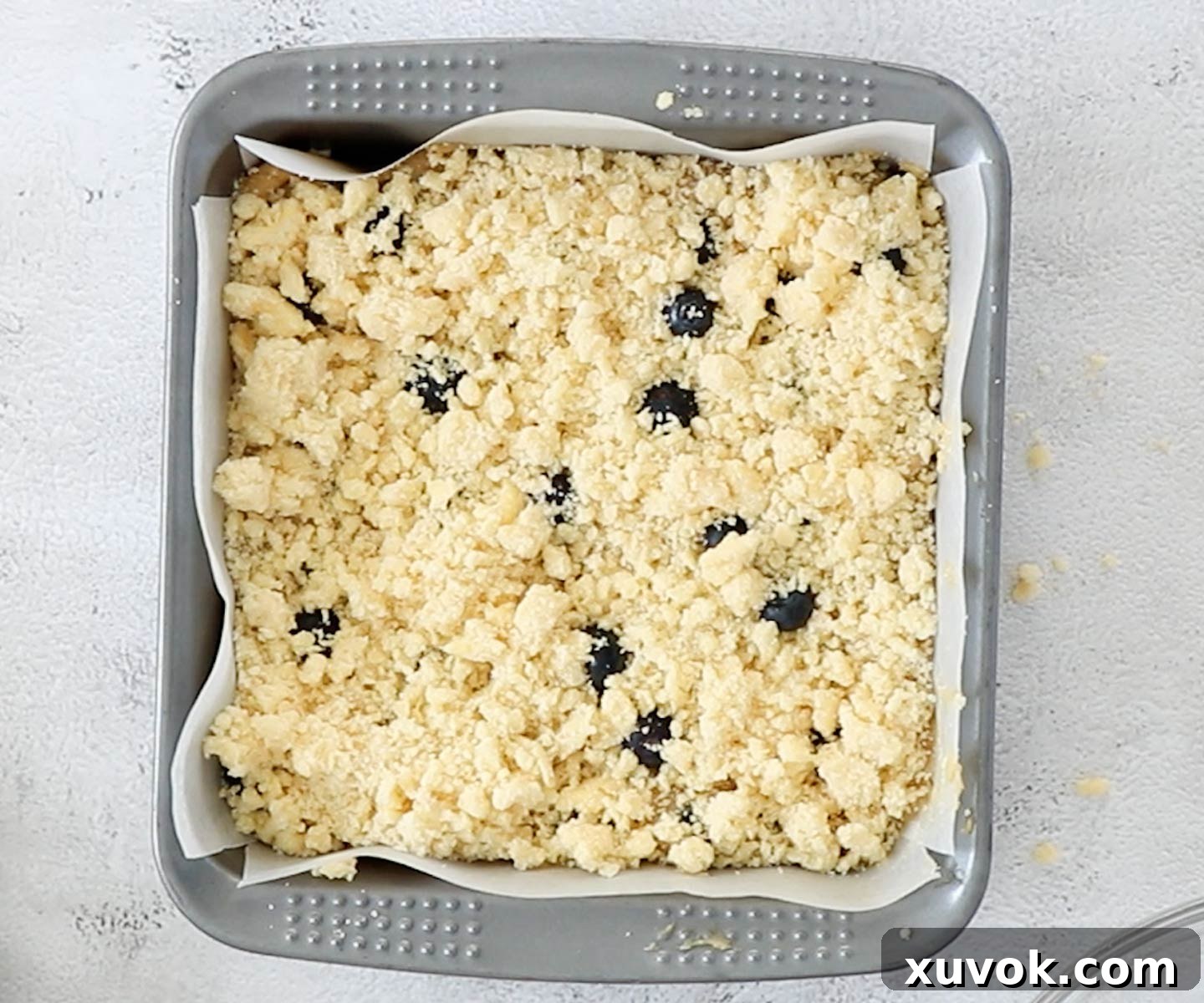 Top down view of the blondie batter topped with streusel crumble in a baking pan, ready for the oven.