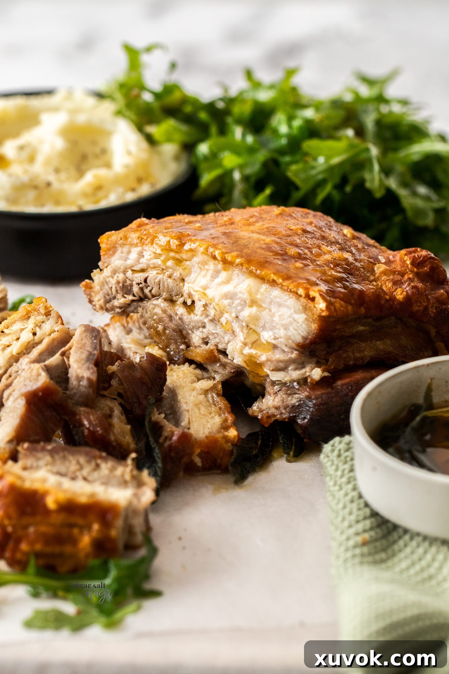 Perfectly sliced oven roasted pork belly with tender meat and golden crispy crackling, served with mashed potato and greens.