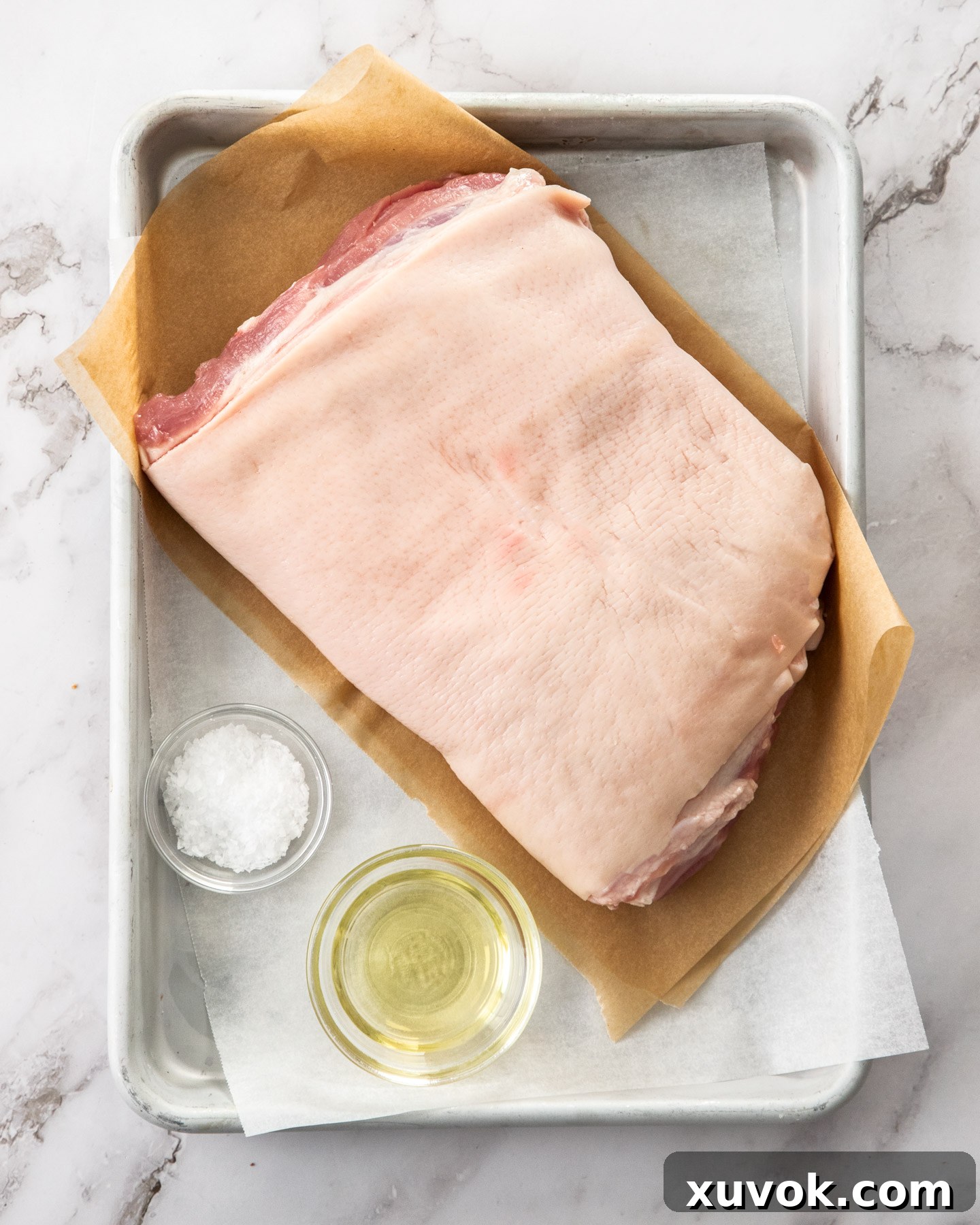 Ingredients for a crispy roasted pork belly recipe laid out on a baking tray.