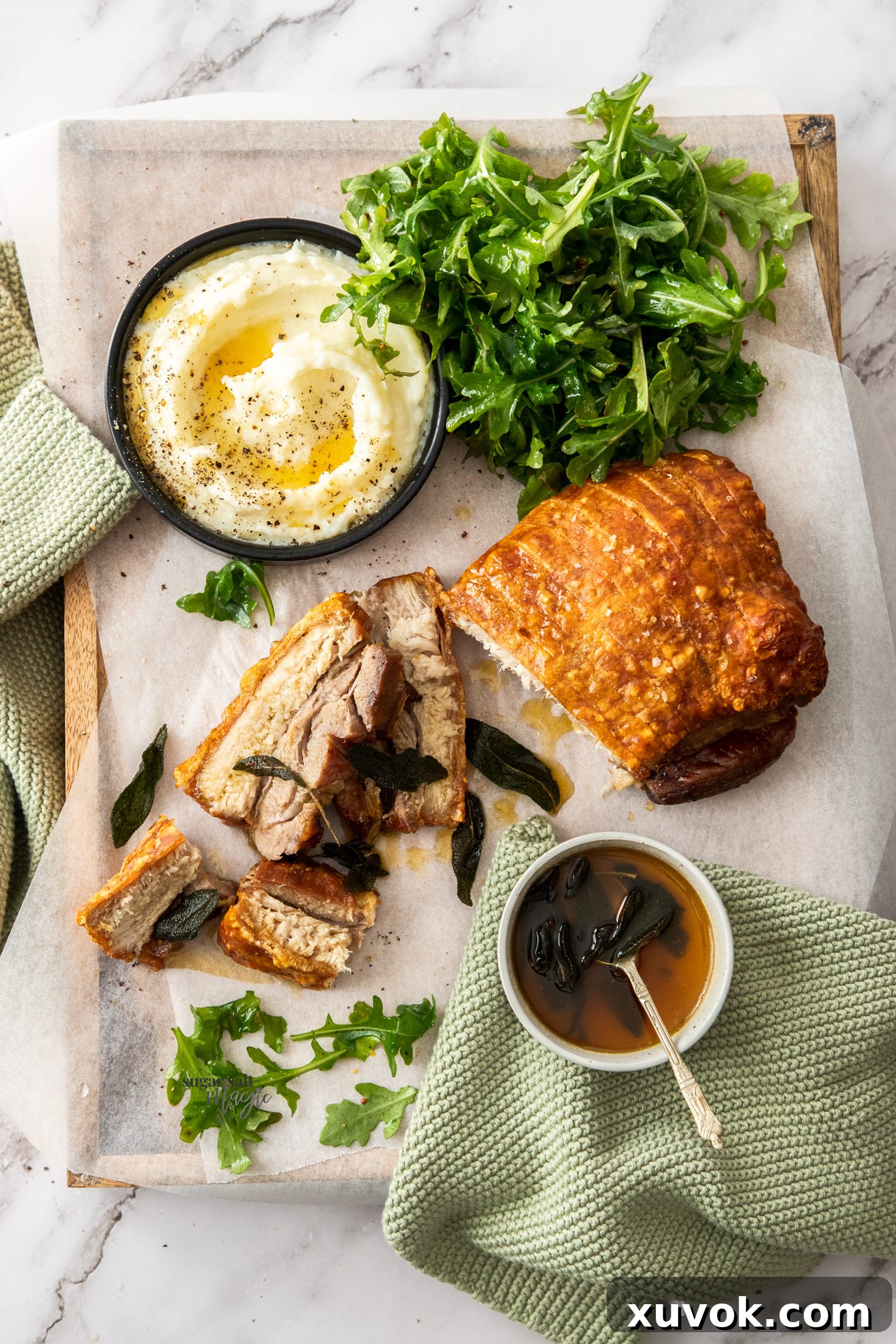 Top-down view of a golden, crispy pork belly roast resting on a wooden cutting board, ready to be sliced.